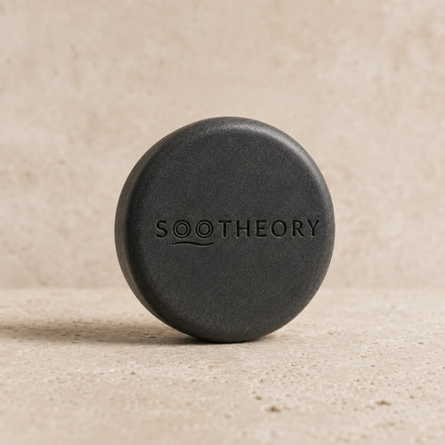 Charcoal gray dog shampoo bar with embossed SOOTHEORY wave logo