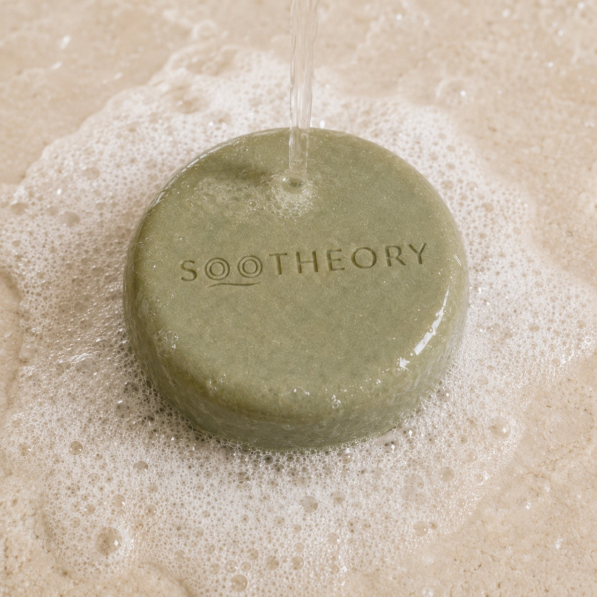 Sage green dog shampoo bar under water with rich white lather